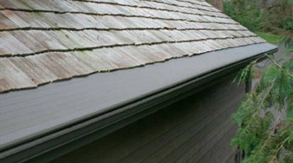 Closeup of roof with shingles and grey gutter.